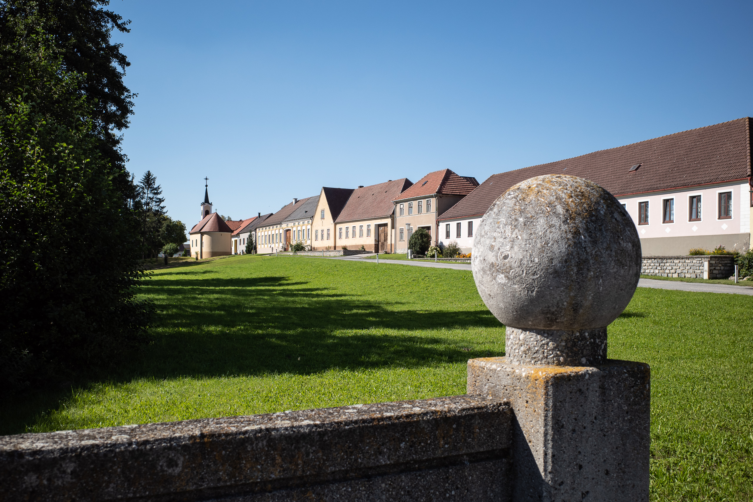 Angerdorf: zwei Häuserzeilen, dazwischen die freie Wiese und die Kapelle